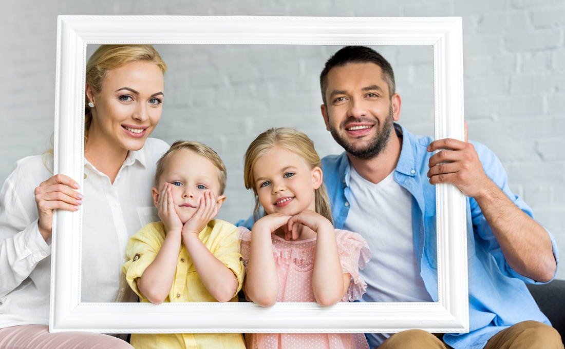 happy family holding frame and smiling at camera